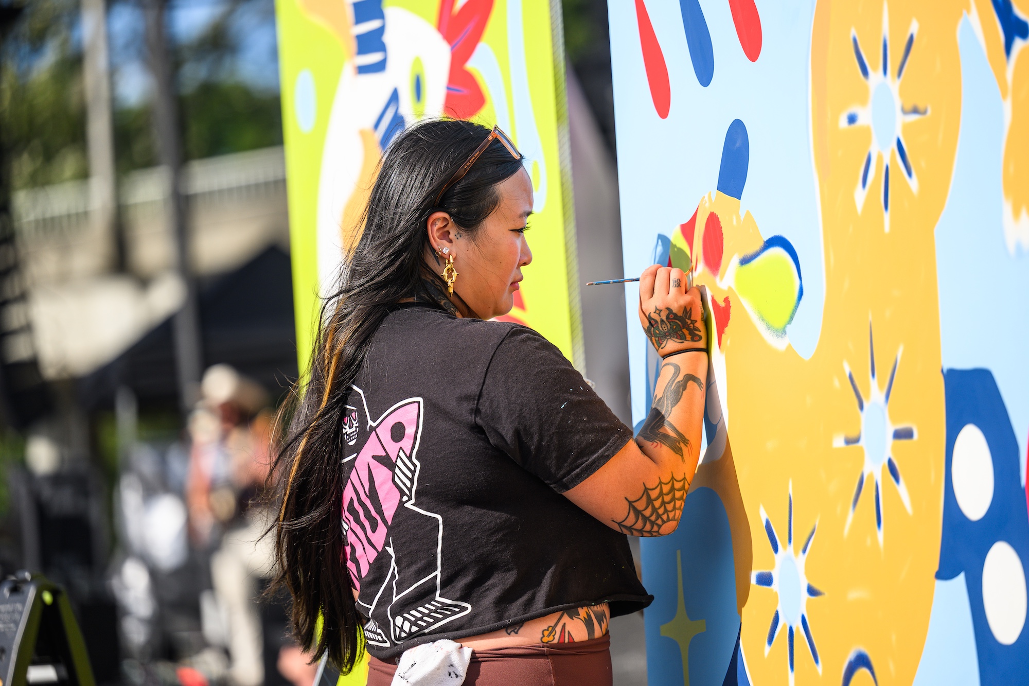 An artist paints a mural during the day at the NW Tune-Up main stage.